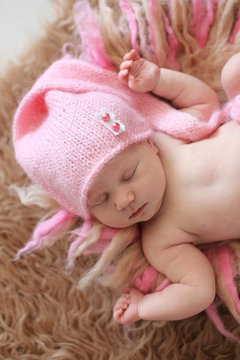 tender newborn baby in pink cap sleeps stretching