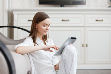 Young attractive girl sitting with a tablet in the hands