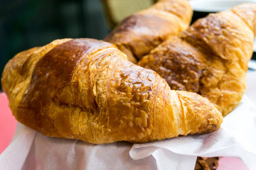 Breakfast with coffee and croissants in a basket on table