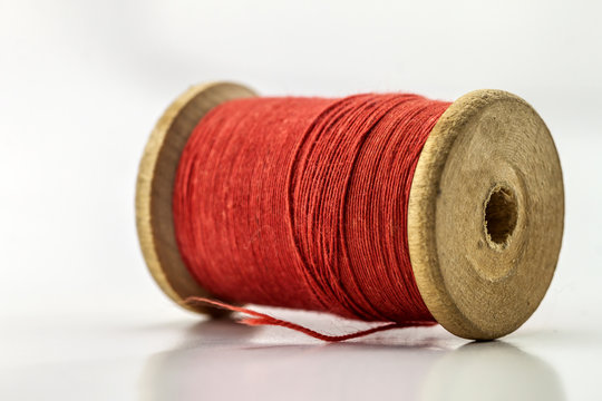 Reel or spool of red sewing thread isolated on white. Shallow depth of field. Close-up macro shot.