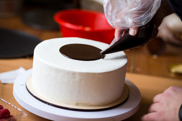Pastry chef in the kitchen decorating a cake of chocolate,fruit,candies,Confectioner is decorating chocolate cake,cooking class, culinary, bakery, food and people concept