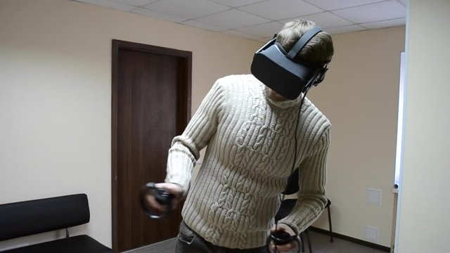 Man with glasses of virtual reality play a game in the office. Man using immersive technology and cybersecurity from virtual reality helmet or vr-headset with headset for fleeting self-expression