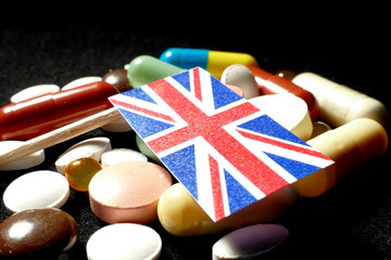United Kingdom flag with lot of medical pills isolated on black background