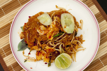 Fried noodle Thai style with prawns on dish. Stand on table have Wood Foundation.