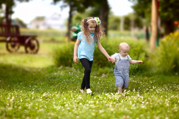 Fototapeta premium Little boy and girl walking hand in hand in the park