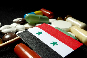 Syrian flag with lot of medical pills isolated on black background