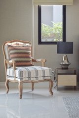 Comfortable claasic style lounge chair next to the bedside table