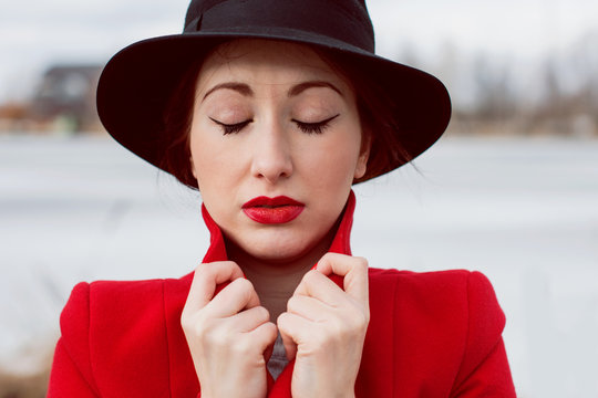 Beautiful french stylish  woman  in black hat and red coat walking in park
