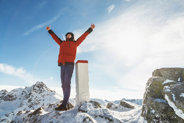 Obraz premium Man on the mountain top raised his hands shouts with joy of his achievements.