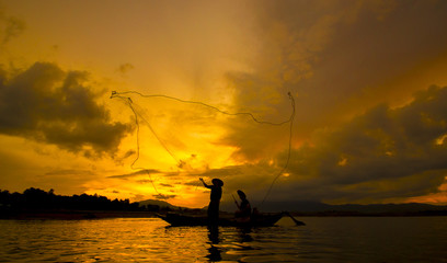Fisherman throwing net at sunrise , Thailand