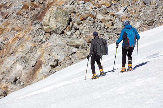 Mountain Climbers Man and Woman walking on steep Ice Slope