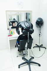 Woman in hairdresser, drying hair under machine