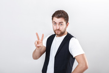Naklejka premium young man with a beard in white shirt and black waistcoat showing number two gesture