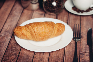 croissant on a white plate fork and knife on the table