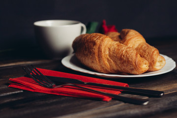 croissants in a plate and a white cup in the background