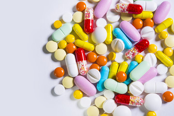 Multicolored pills and tablets on white background
