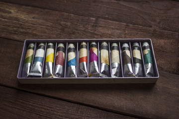 Tubes of oil paint in box . Wooden background