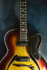 Fototapeta na wymiar Close-up of old electric jazz guitar on a dark blue background
