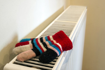 Childs knitted gloves drying on heating radiator after winter day outside
