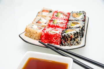 sushi and chopsticks lying on a white plate 