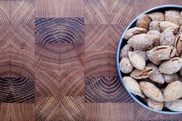 snack salted almonds in shell in metal plate on wooden chef's Board top view