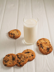 glass of milk and cookies with chocolate on a white wooden background