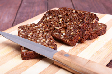 Sliced black bread and knife on the old wooden plank