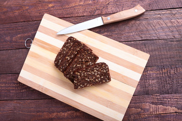 Sliced black bread and knife on the old wooden plank