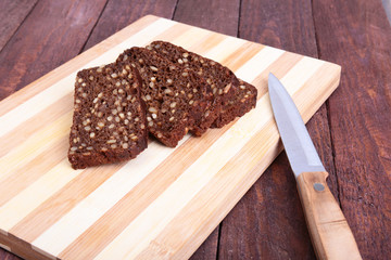 Sliced black bread and knife on the old wooden plank
