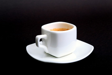 Cup of espresso coffee on white plate, isolated on dark background