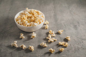 popcorn in a white plate on a concrete gray background