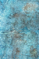 A rusty old metal plate with cracked blue gloss paint