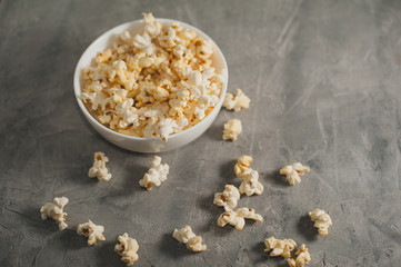 popcorn in a white plate on a concrete gray background