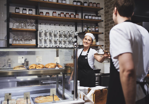 Bartender and waiter working together at coffee shop and smiling.