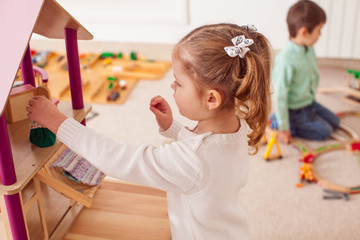 Girl playing with a dollhouse - obrazy, fototapety, plakaty