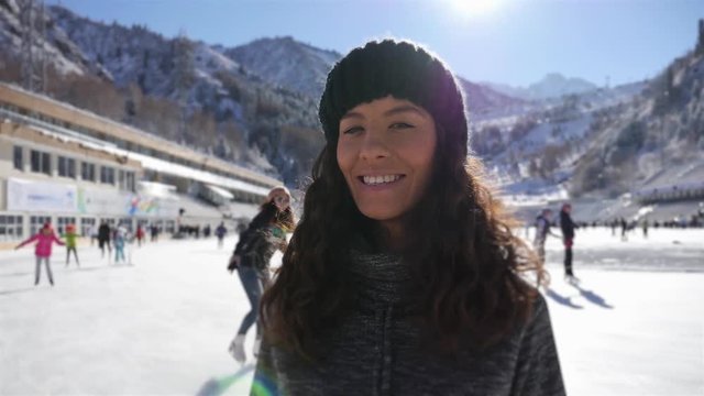 Happy young woman looking at camera, ice skating girls at rink