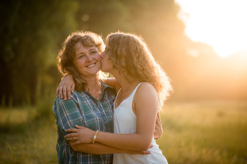 Teenage daughter kissing her mature mother