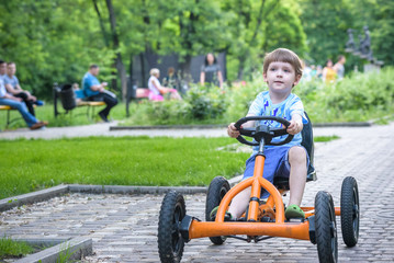 Little preschool boy driving big toy sports car and having fun, outdoors.