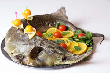 Sturgeon with oranges, spinach, cherry tomatoes and physalis . Baked whole. Selective focus.