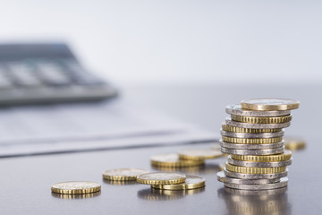 Euromünzen und Taschenrechner auf spiegelnder Tischplatte