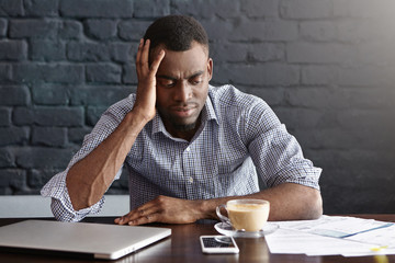 Unhappy African businessman feeling stressed and frustrated, facing financial troubles, leaning...