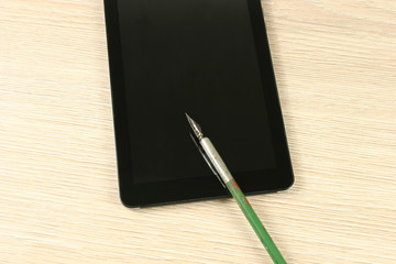 fountain pen and tablet computer on wooden table
