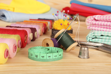 On the table are a tailor: spools of colored thread, measuring tape, needles, scissors, pieces of...