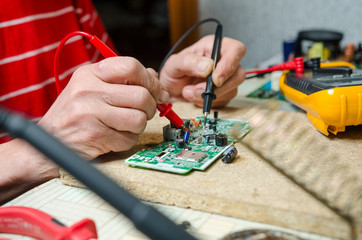 man hands closeup repair electronic device using Multimetr. tools