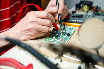 Fototapeta na wymiar man hands closeup repair electronic device using Multimetr. tools