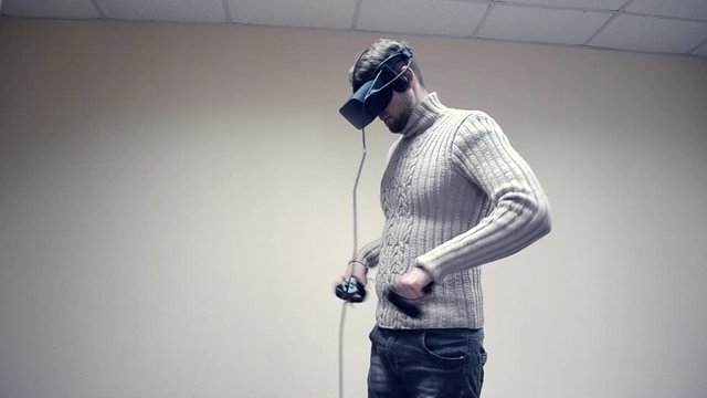 Man in a virtual reality headset play a game in the office. Man using immersive technology and cybersecurity from virtual reality helmet or vr-headset with headset for fleeting self-expression
