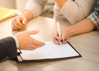 Closeup toned of woman signing agreement or contract in office interior. Salesman offering contract for purchase or sale. Apartment. Flat. Automobile.