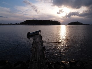 島のシルエットと夕日　古い桟橋と漁船
