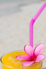 Mango cocktail with pink flower on the sunny beach