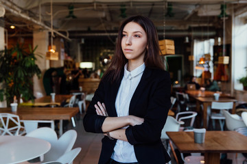 Portrait of a young cute brunette girl business in the interior hipster cafes. Long hair.